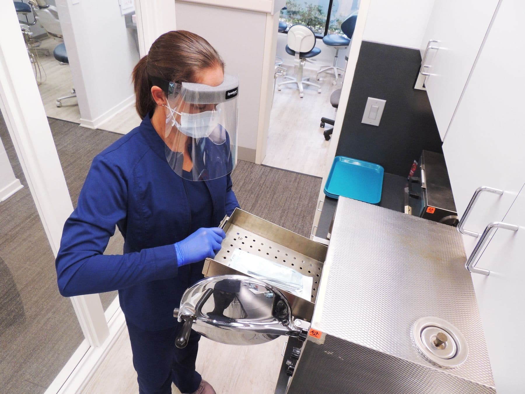 Dental assisting student loading an instrument cassette into the autoclave during sterilization training